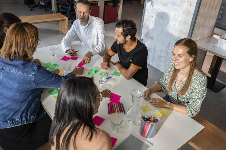 personen werken met post-its aan tafel