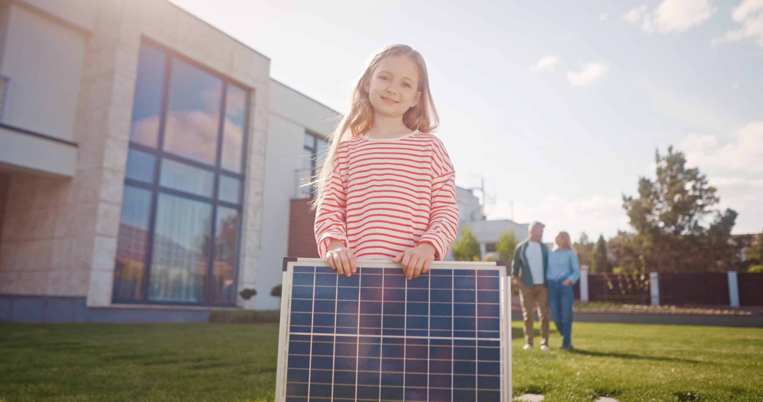 Blij meisje met zonnepaneel kijkt in de camera met blije ouders op de achtergrond